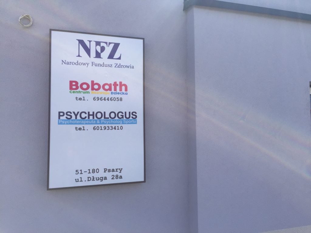 reklama pionowa przykręcona do budynku nfz, bobath, psychologus