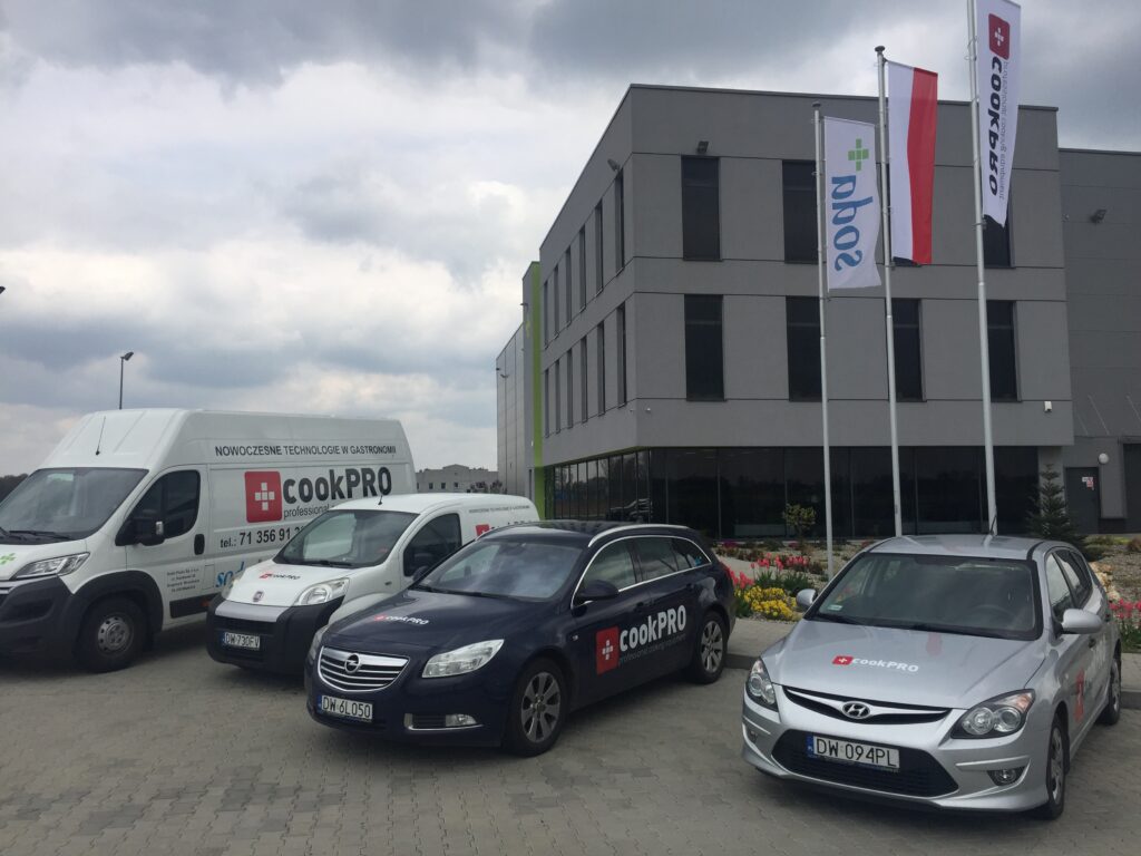 biurowiec firmy soda plus przed nim na parkingu oklejone reklamami auto dostawcze fiat boxer, fiat nemo, opel insignia, hyundai i30